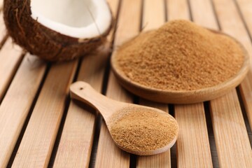 Coconut sugar, spoon, plate and fruit on wooden table, closeup