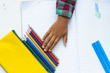 In school, in classroom, young biracial boy is selecting colored pencils