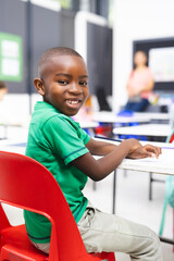 In school, young African American boy sitting in classroom, smiling at camera