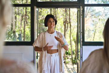 Young Hispanic woman yoga coach training group class yoga meditation session sitting in yoga pose...
