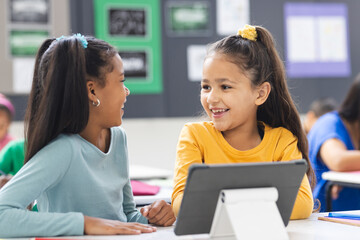 In school, biracial teacher guiding her diverse students during lesson in classroom