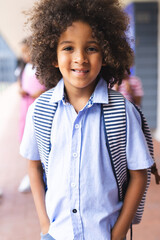 In school, young African American boy with curly hair is smiling outdoors