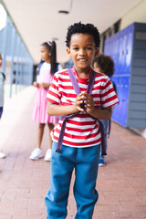 In school, young African American boy is standing, smiling outdoors