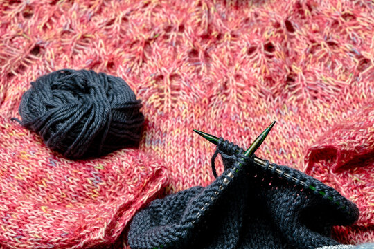 texturas de tejido de lana rosada con madeja de lana gris y palillos