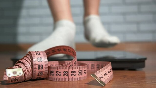 Girl measuring perfect waist. A view of teen with sporty waist measuring on the scale in the room.