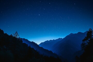 Naklejka premium Silhouetted trees against dark sky and mountain backdrop. Evening landscape concept