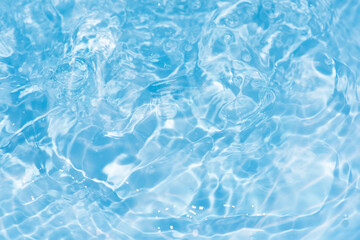Blue water with ripples on the surface. Defocus blurred transparent blue colored clear calm water surface texture with splashes and bubbles. Water waves with shining pattern texture background.