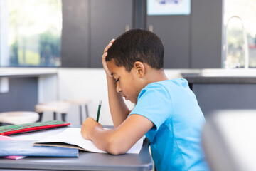 Biracial boy focused on schoolwork in the classroom at school