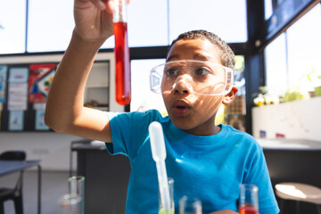 Biracial boy examines a test tube in a school science lab