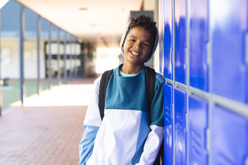 Biracial boy stands by school lockers, with copy space