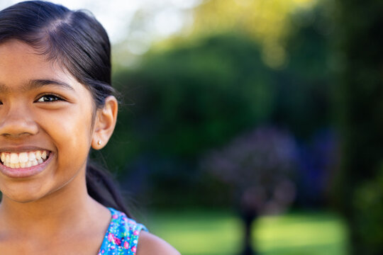 Outdoors, young biracial girl smiling brightly with colorful dress, copy space