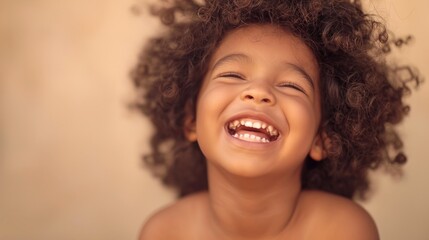 A young child with curly hair smiles joyfully.