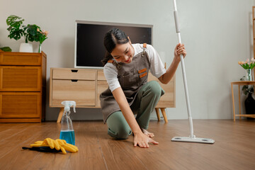 housewife is mopping the floor in the house to remove dust and keep it hygiene for everyone in the family safe, a wife is wearing apron to clean and make the living room neat