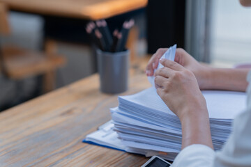 Cropped shot of hand holding pen and using laptop to work at table in office