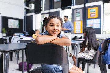 Biracial girl with braided hair smiles in a school classroom setting