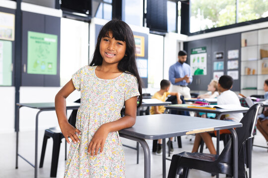 Biracial girl with long dark hair stands confidently in a school classroom with copy space - Powered by Adobe