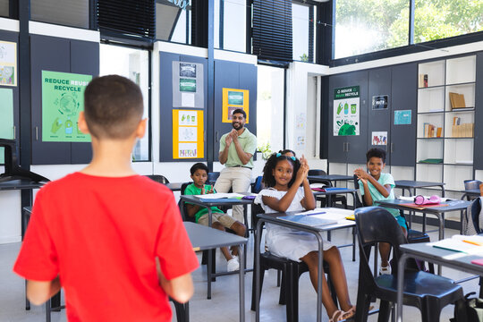 In school, young Asian male teacher and diverse young students are learning