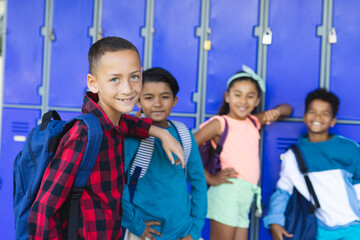 Diverse children stand by school lockers, smiling