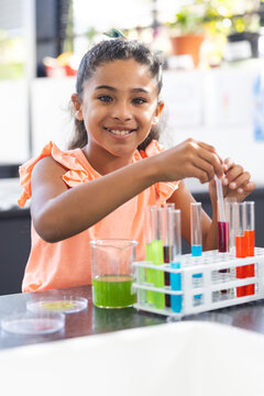 In school, young biracial female student is conducting a science experiment