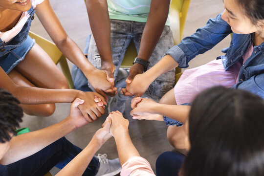 Diverse teenagers join hands in a show of unity at high school