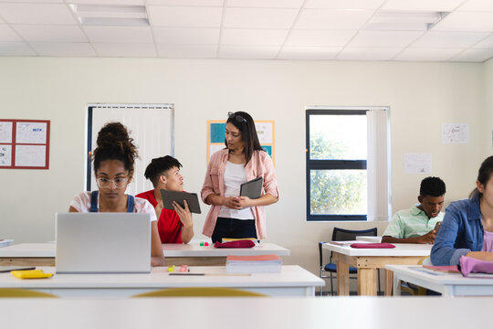 Young biracial woman teaches in a bright classroom in high school