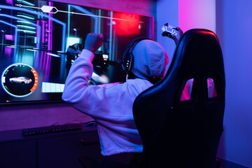 A biracial young female wearing headphones, gaming at home