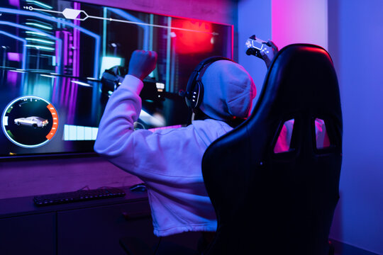 A biracial young female wearing headphones, gaming at home