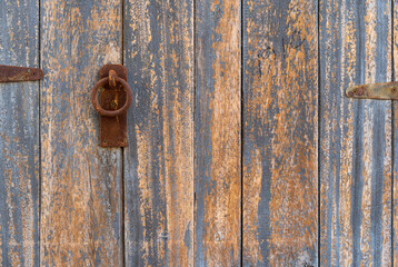 vintage rusty iron door knocker or metal on old brown blue peeling paint wood door retro style or ancient house wooden doors lock to close for interior wall background and home texture architecture