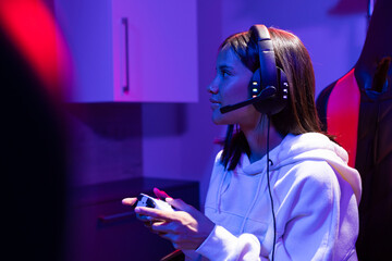 A biracial young girl wearing headphones, gaming at home