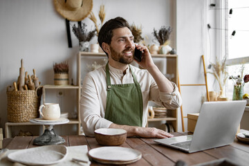 Successful businessman owner of shop made of clay talking to customer. Caucasian male potter...