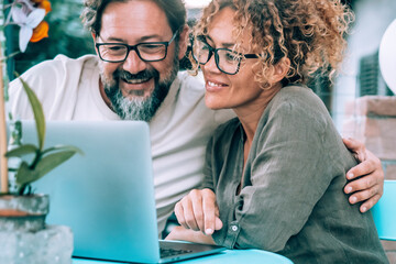 Happy serene couple in love using laptop together at home in the garden smiling and having fun. Man...