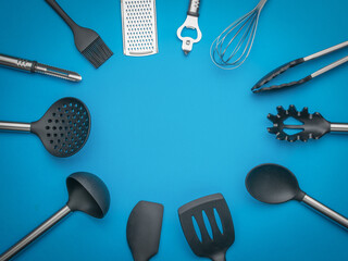 Top View of Assorted Kitchen Utensils Arranged in Circle on Blue Background