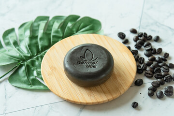 Handmade soap bar with coffee as show word meaning ''natural 100%'' on white table