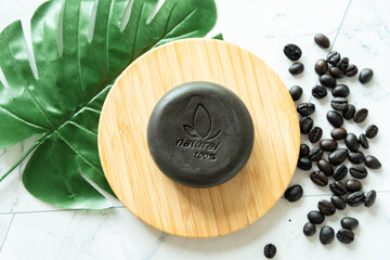Handmade soap bar with coffee as show word meaning ''natural 100%'' on white table