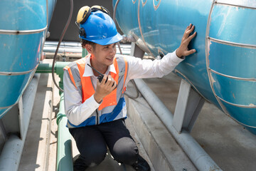 Portrait Asia male engineer in protective workwear is performing a conducts system check with use walkie talkie at rooftop building	