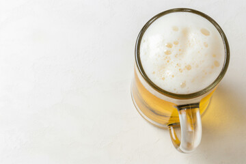 A glass mug filled with a golden yellow beer, topped with a white foam.