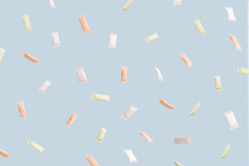 Different snus sachets with different flavors spill out of a plastic jar.