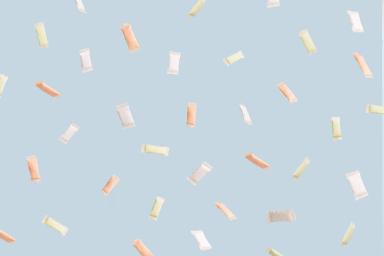 Different snus sachets with different flavors spill out of a plastic jar.