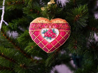 A cross stitched Christmas Timeless Elegance ornament on to a Christmas tree. This heart shape...