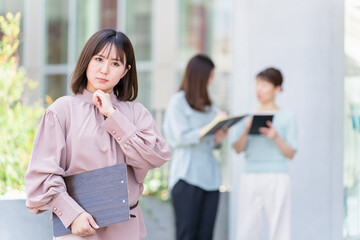 オフィスビルの前で考える・悩む・困るビジネスウーマン・女性
