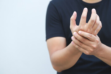 Closeup of male arms holding his painful wrist caused by prolonged work office syndrome. rheumatoid...