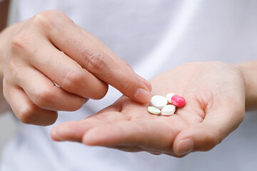 close up hand man taking multiple pills take a medicine in hand holding a cup glass of drinking water on wooden table. Stop drug use Taking Medication health care medical concept..