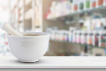 Mortar and pestle on pharmacy counter top with blur medicine shelves in drugstore background