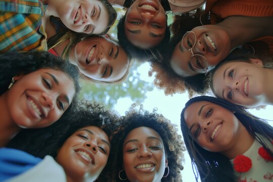 A diverse group of friends stands happily in a circle outdoors, showcasing unity and friendship among multicultural individuals. They exude positivity, social interaction, and joy