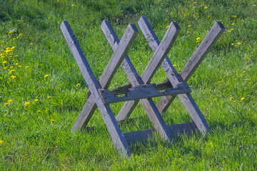 Sawhorses for sawing firewood stand on a green lawn.