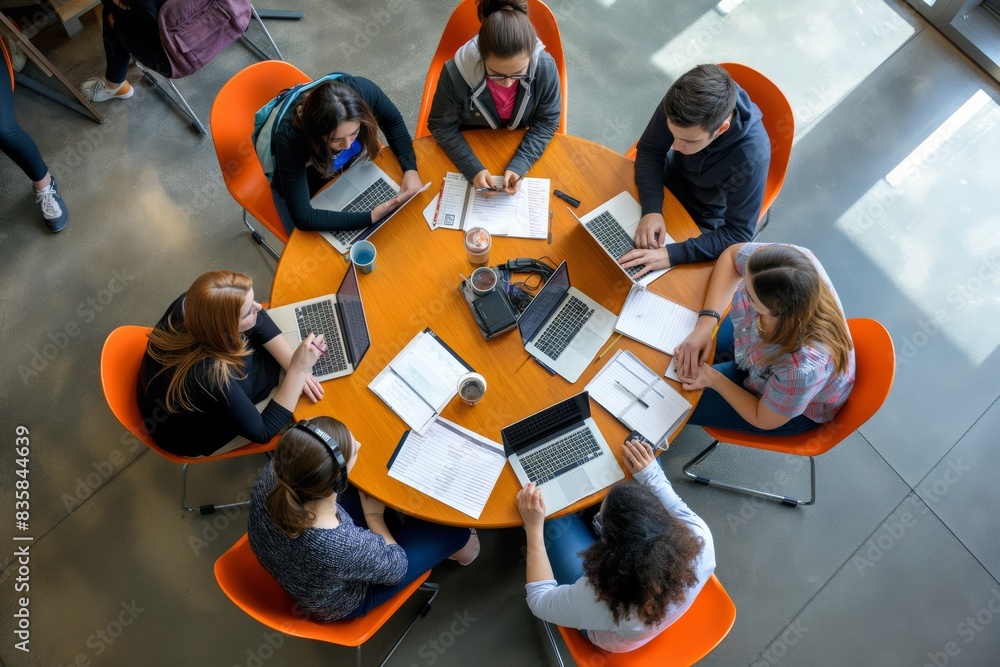 Aufkleber Collaboration in modern workspace involves a team meeting around a round table with laptops and notes. It is a setting for teamwork, discussion, and brainstorming among professionals using technology