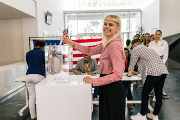 Young woman voter placing ballot in ballot box polling place in America.