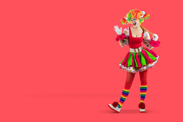 Funny female clown club-swinging. Entertainer woman Joker in colorful suit and wig. Buffoon with clown whiteface makeup. Trickster, jester, pantomime, mime. Professional actor.