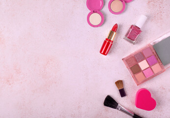 Pink makeup flat lay with eyeshadow palette with warm colors, lipstick, nail polish, heart shaped...