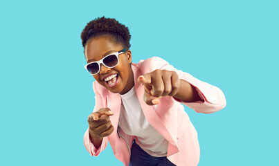 Portrait of happy confident young woman in stylish party outfit. Positive beautiful Afro American lady wearing fashionable pink suit and cool sunglasses looking at camera, smiling and pointing at you